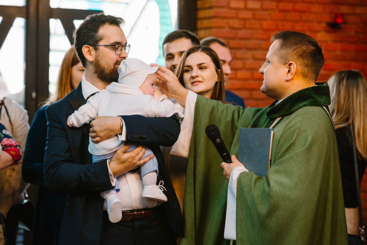 ksiądz błogosławi dziecko podczas chrztu
