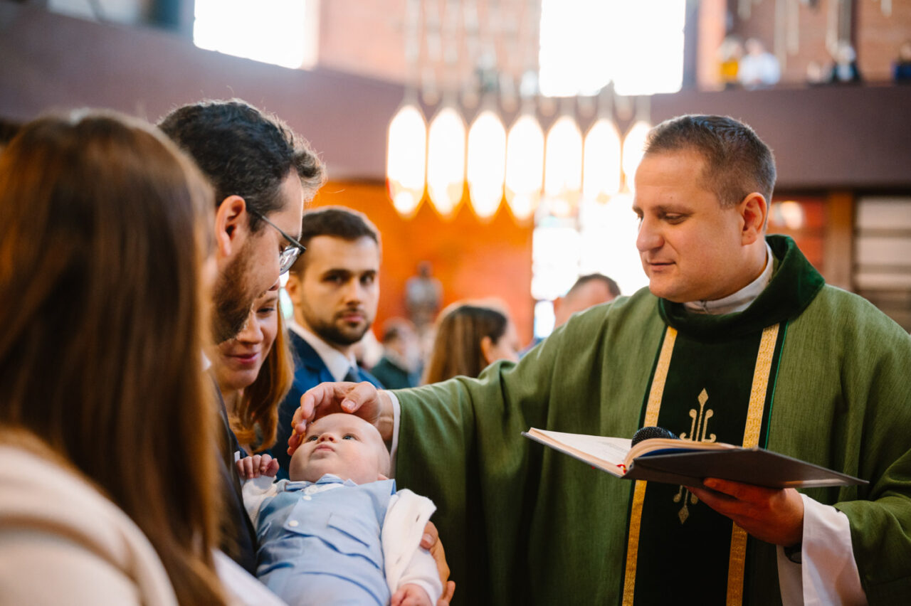 ksiądz z parafii Boboli naznacza dziecko podczas Chrztu