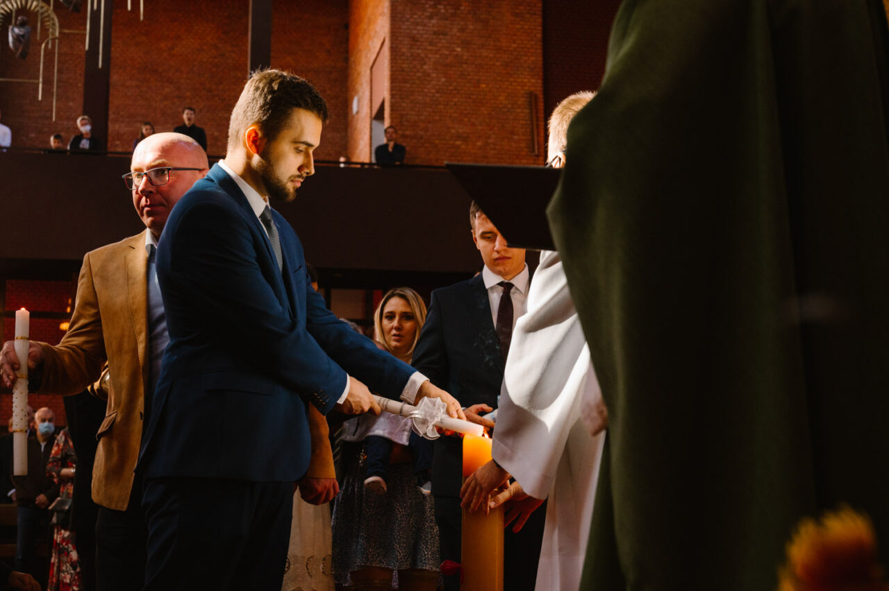 ojciec chrzestny odpala świecę od paschału