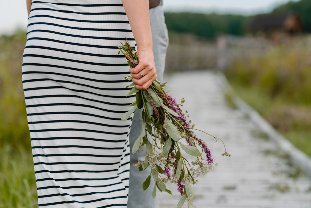 kobieca dłoń trzymająca bukiet polnych kwiatów