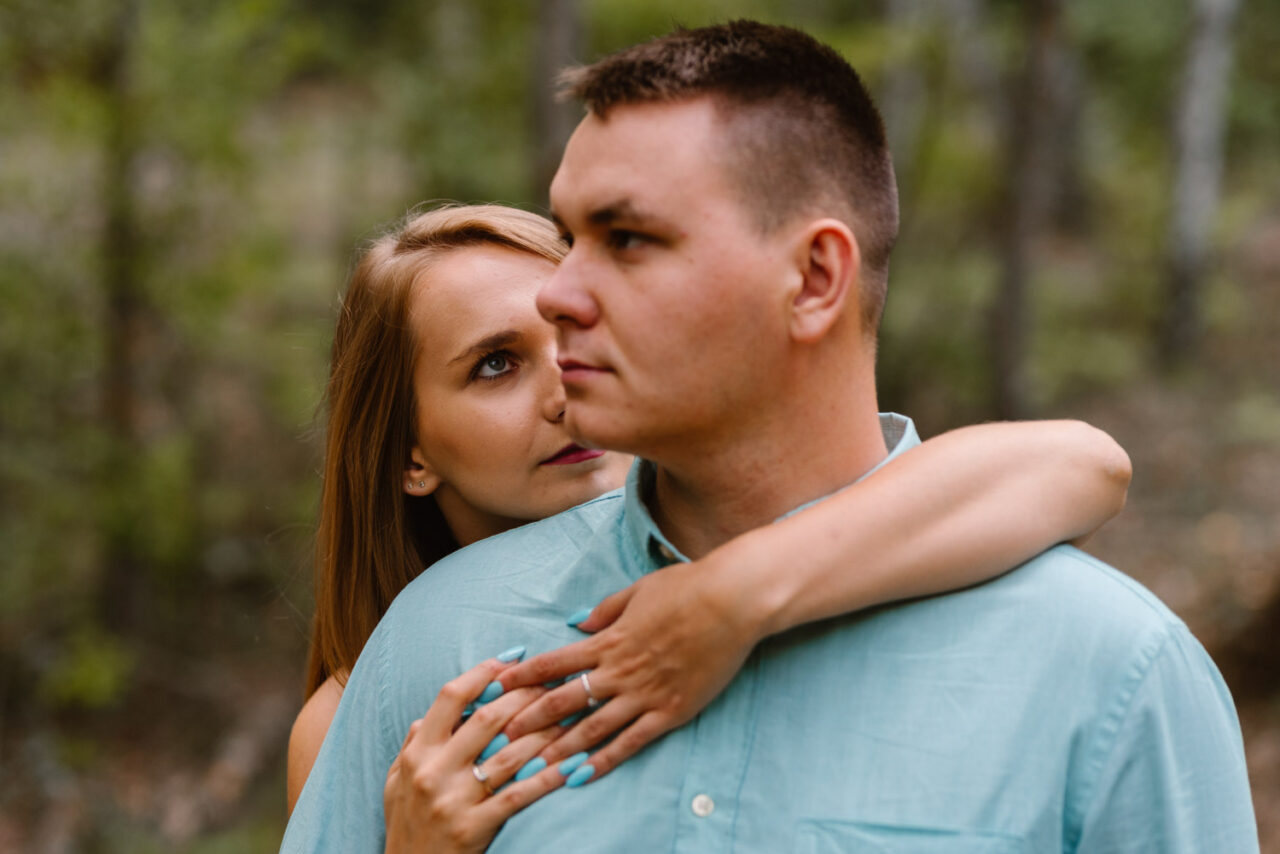 portret mężczyzny w którego wpatruje się narzeczona na tle lasu
