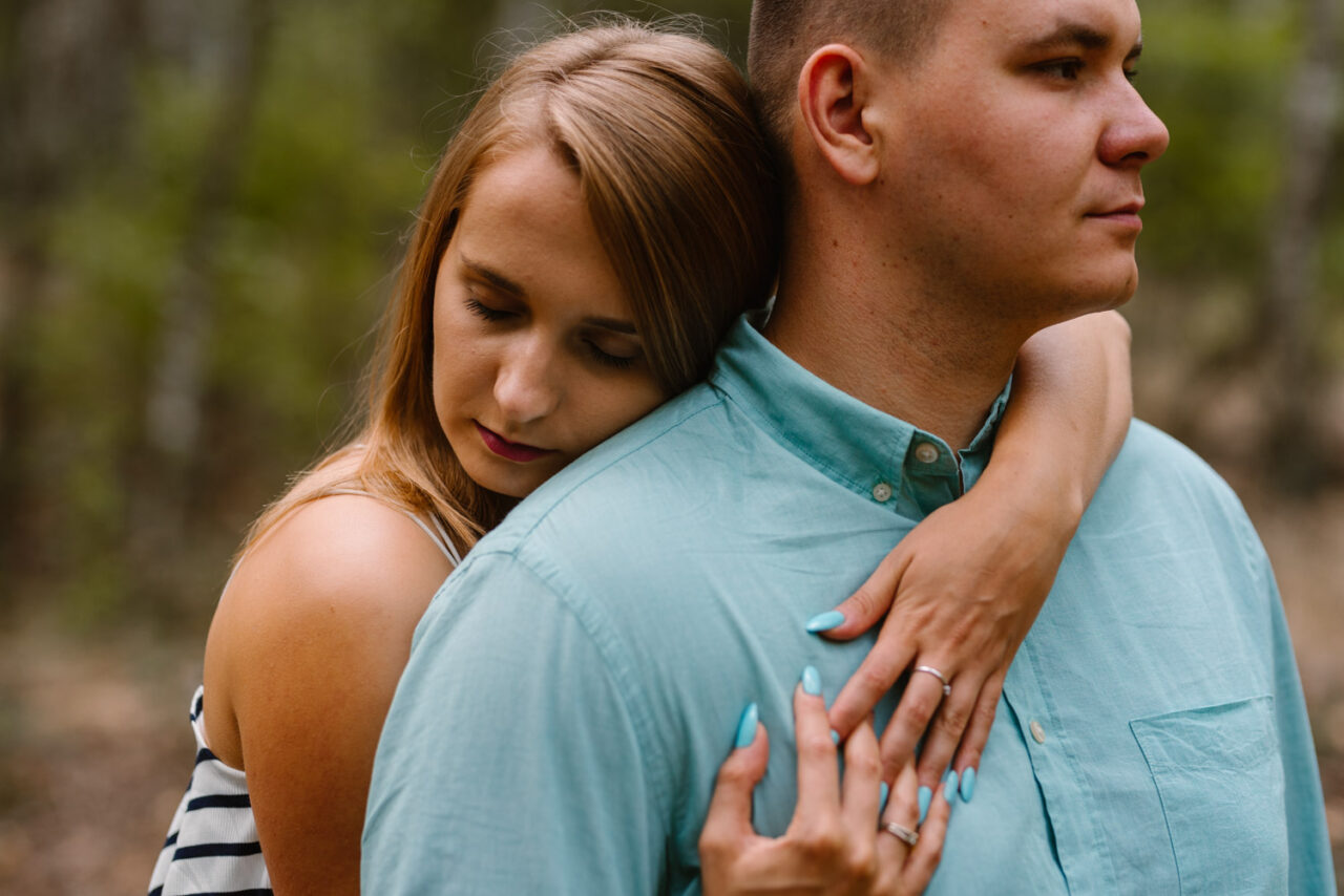 narzeczona obejmuje swojego ukochanego na tle lasu