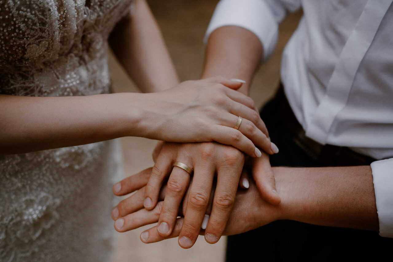 dłonie pary młodej z obrączkami i pierścionkiem zaręczynowym