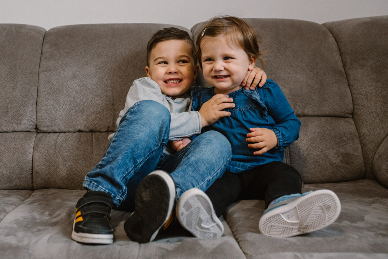 radosne rodzeństwo przytula się na kanapie