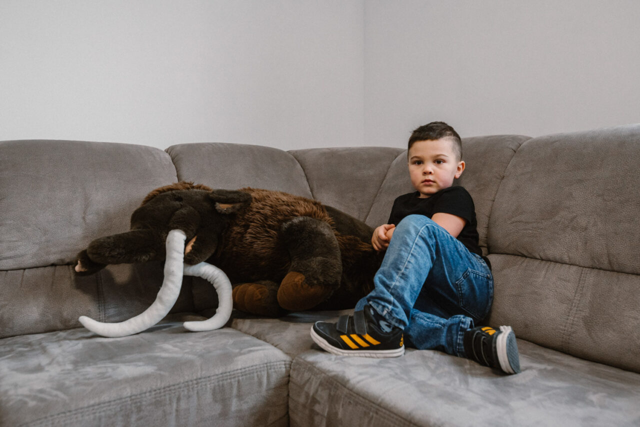 chłopak pozuje z pluszowym mamutem