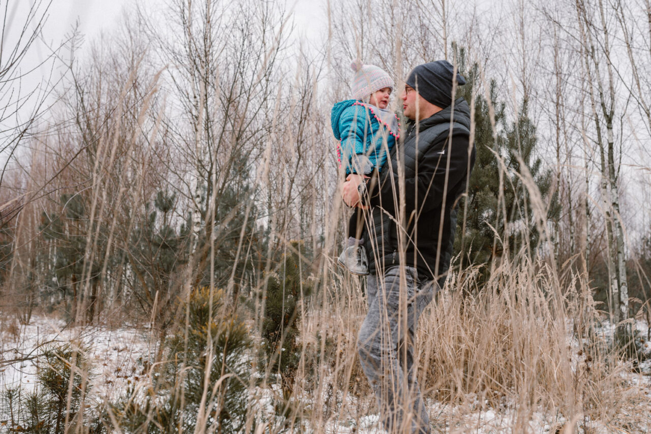 ojciec noszący córkę na ramionach zimą